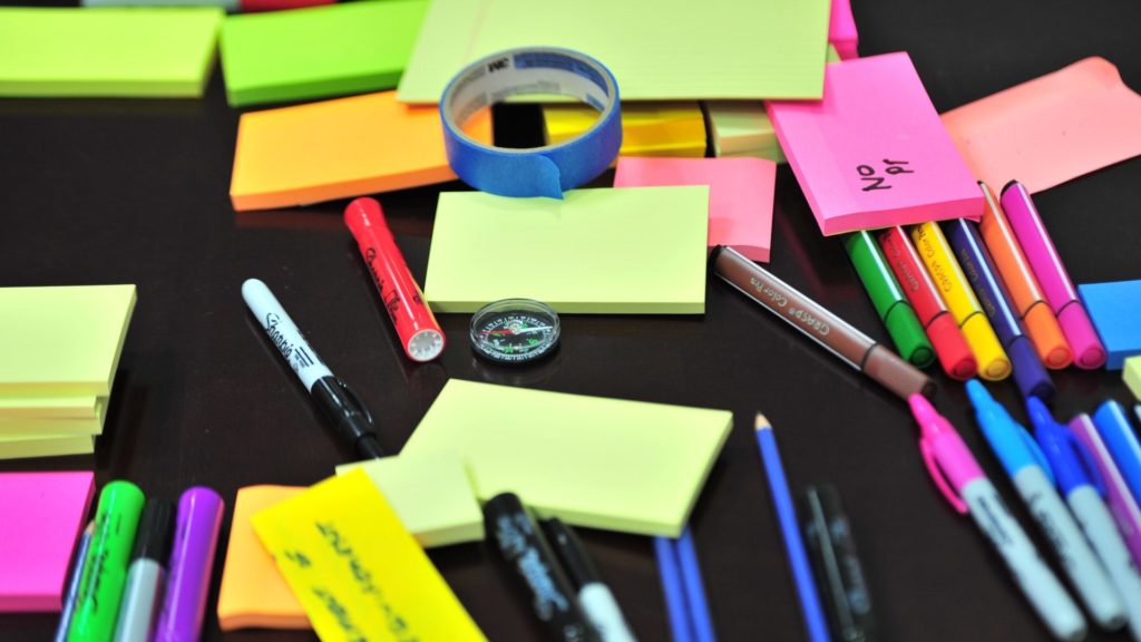 Post it notes of various colours with pens and pencils ready for a brainstorming session.